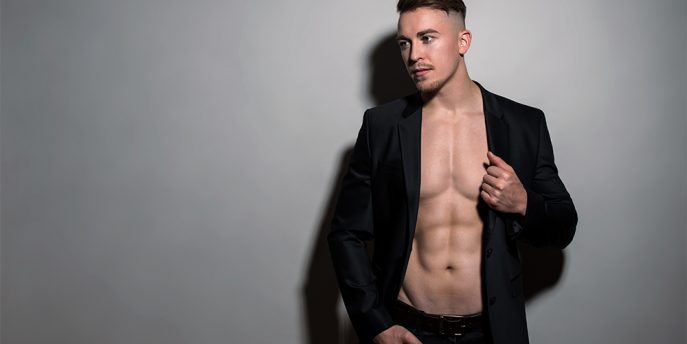 Handsome young and fit bodybuilder wearing suit jacket on grey background